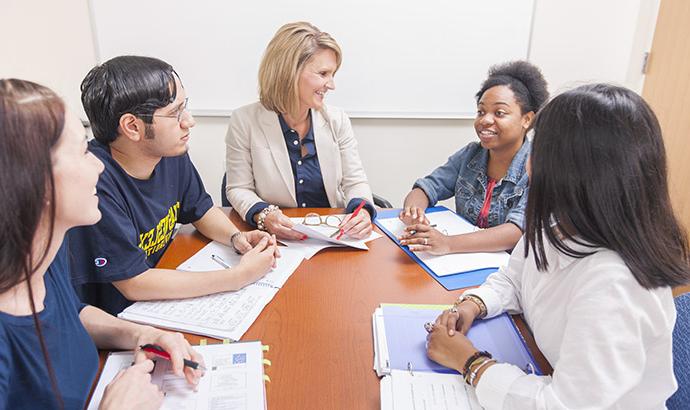 a professor speaking with students at a round table